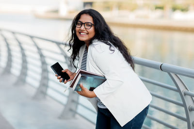 An indian girl is walking around the city and talking on the phone.