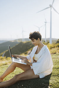 Smiling woman using laptop while sitting on mountain