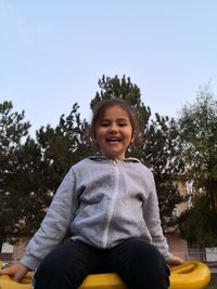 Portrait of smiling girl sitting against trees