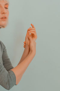 Young woman with eyes closed massaging her hand against white background