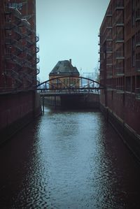 Bridge over river by buildings against sky in city