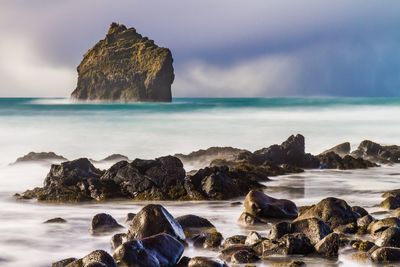 Scenic view of rocks on beach against sky
