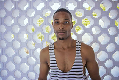 Portrait of young man standing against wall