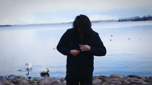 Woman standing in lake against sky during winter