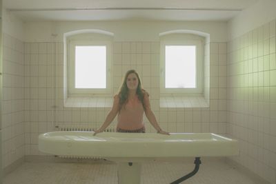 Portrait of woman standing by bathtub in bathroom