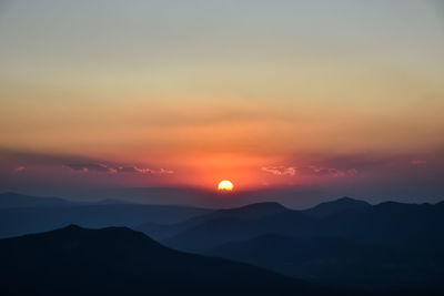 Scenic view of silhouette mountains against romantic sky at sunset