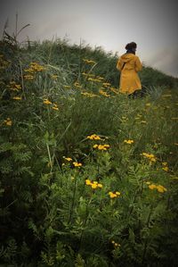 Rear view of woman standing on field against sky