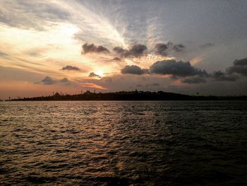 Scenic view of sea against cloudy sky at sunset