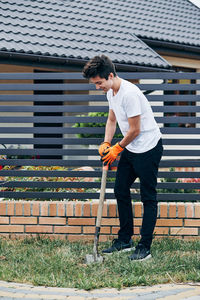 Side view of young man standing against built structure