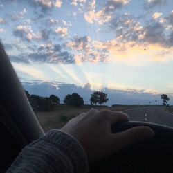 Midsection of person holding car against sky during sunset