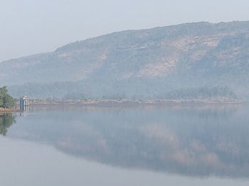 Scenic view of lake by mountains against sky