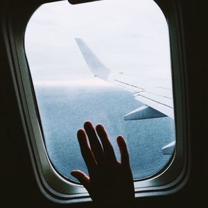 Cropped hand touching window in airplane