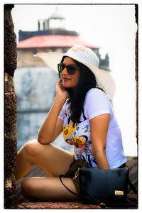 Woman wearing sunglasses and hat while sitting outdoors