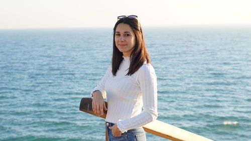 Portrait of smiling young woman standing in sea