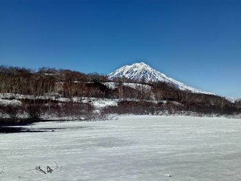 Scenic view of frozen lake against clear blue sky