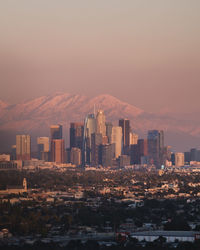 Modern buildings in city against sky during sunset