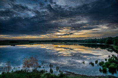 View of calm lake against cloudy sky during sunset