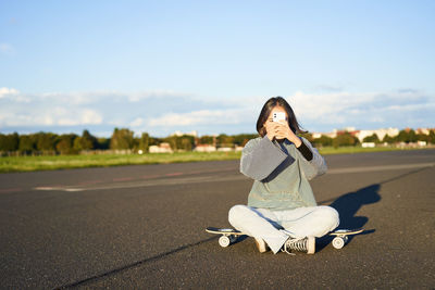 Side view of young woman sitting on road