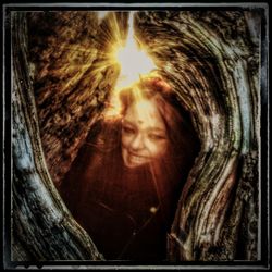 Portrait of smiling woman with tree trunk