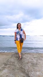 Full length of woman standing at beach against sky