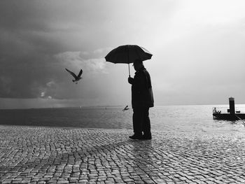 Man with umbrella on coast