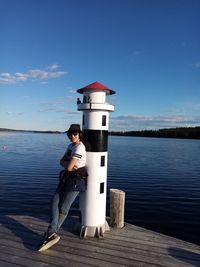 Side view of man on pier over lake against sky