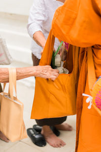 People putting flowers in monk bag