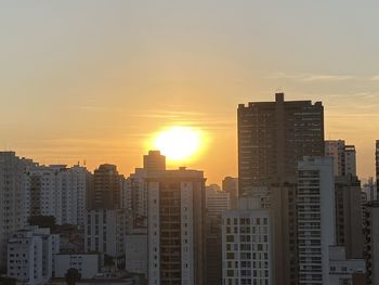 Modern buildings in city against sky during sunset
