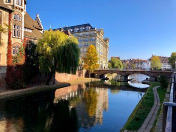 Bridge over river by buildings against sky in city