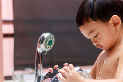 Close-up of boy taking shower at home
