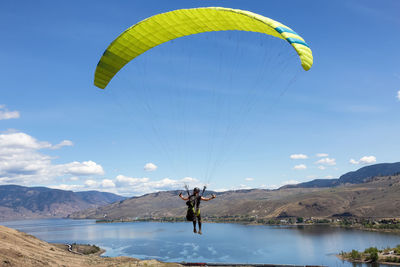 Man paragliding over mountains against sky