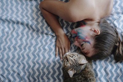 Woman lying with cat on bed at home