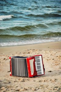 Red accordion on sand at beach