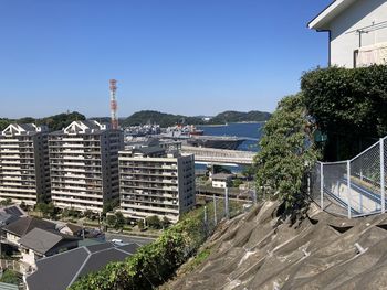 Buildings by sea against clear sky