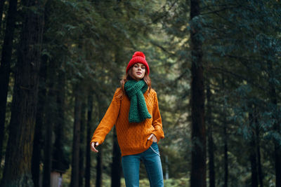 Portrait of young woman against trees in forest