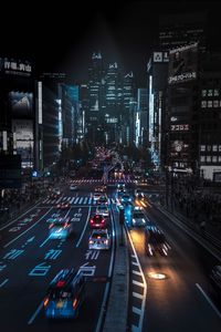 Traffic on city street by buildings at night