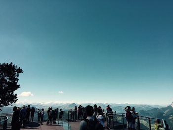 People at observation point against blue sky