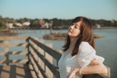 Young woman looking down while standing by railing