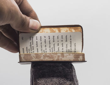 Cropped hand holding bible on white background