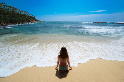 Rear view of woman sitting on beach