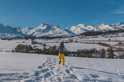 Rear view of man walking on snow covered mountains
