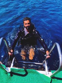 High angle portrait of smiling man climbing steps on boat