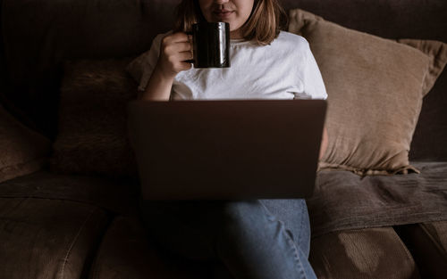 Midsection of man using phone while sitting on sofa at home