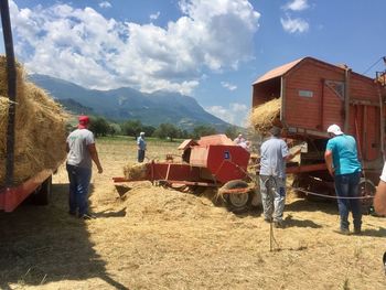 People working on field against mountain