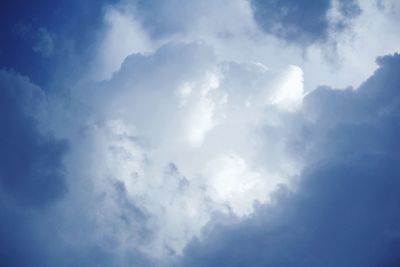 Low angle view of sunlight streaming through clouds