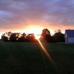 Scenic view of grassy field against sky at sunset