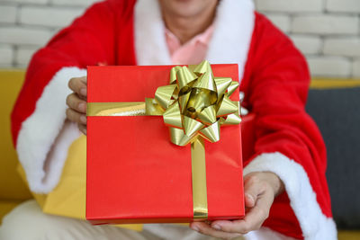 Midsection of man holding red christmas decoration in box