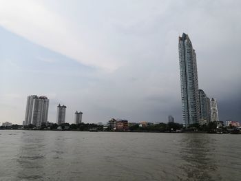 Modern buildings by  chao phraya river  against sky