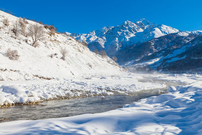 Scenic view of snowcapped mountains against clear blue sky