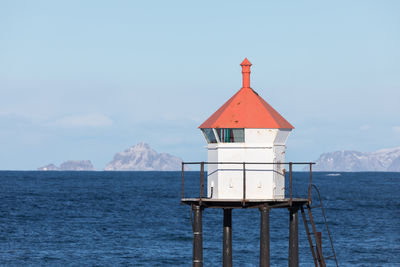 High section of typical norwegian lighthouse on a sunny winter day against rocky islands in sea